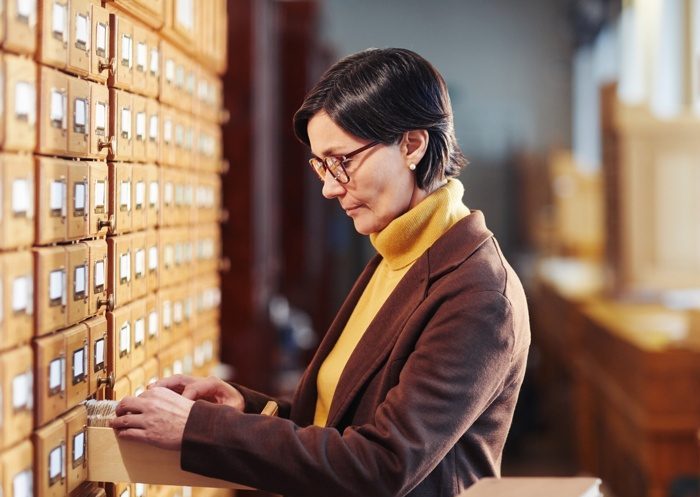 side-view-portrait-female-librarian-searching-book-library-catalogue-cabinet